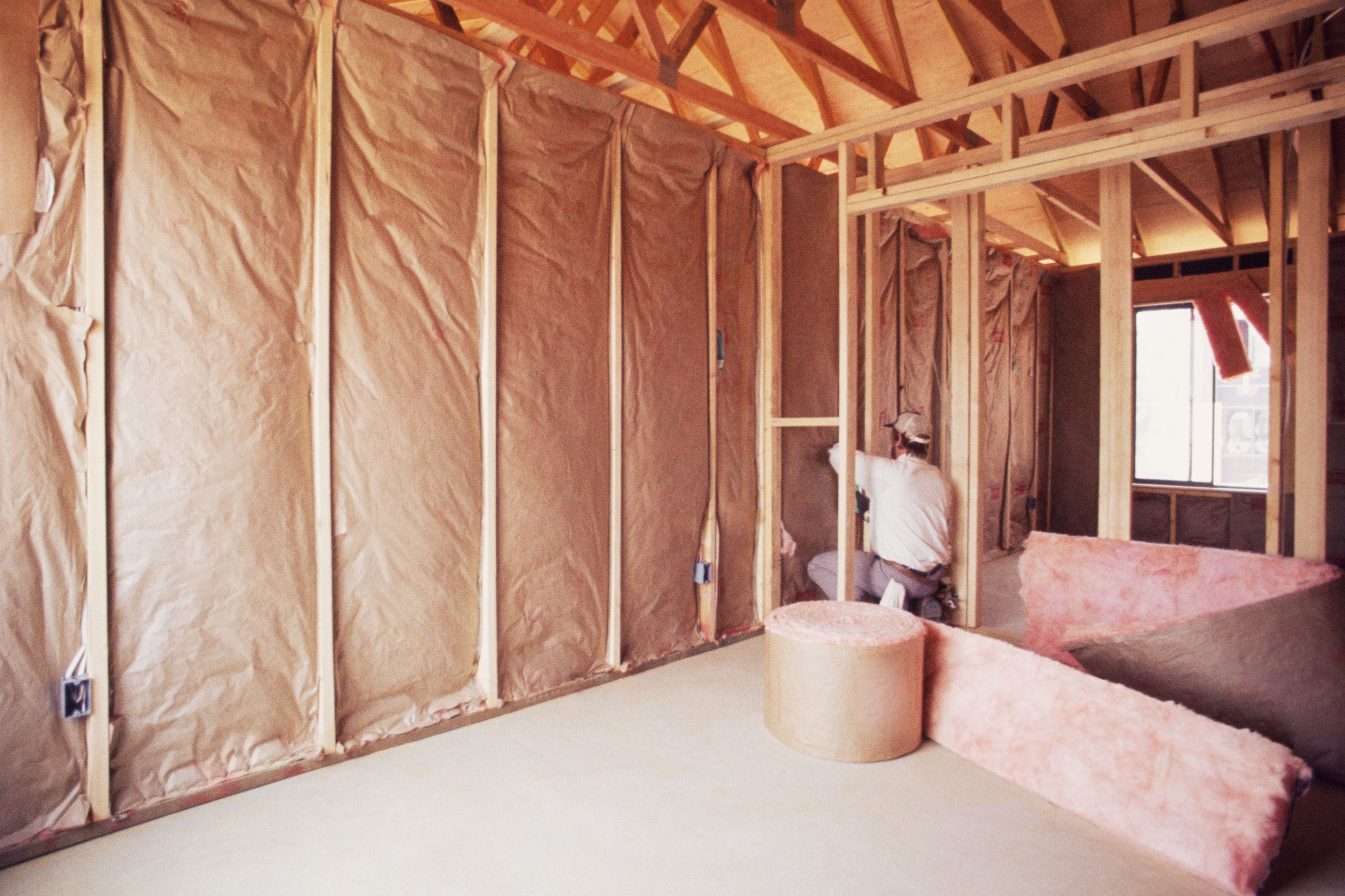 Man installing insulation in an unfinished attic